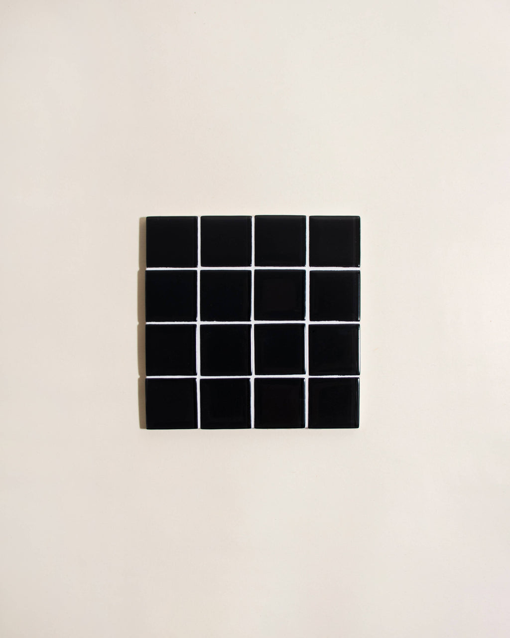 Black square tile with grid pattern on a beige background